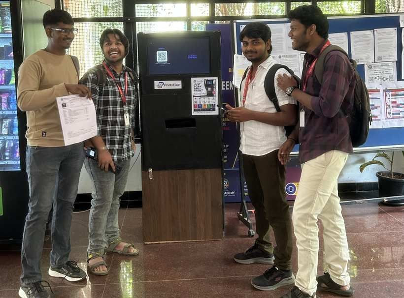 Four students next to the PrintnFlow kiosk at BMSIT&M, one holding a freshly printed document