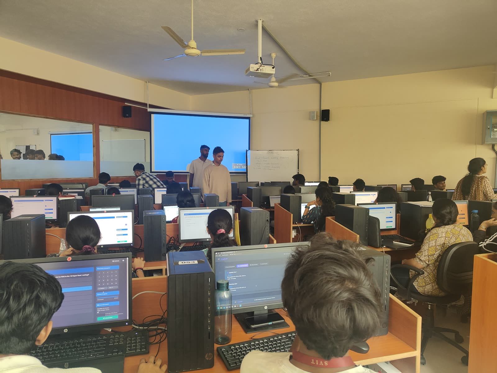 An instructor walking the room while students follow along on their machines